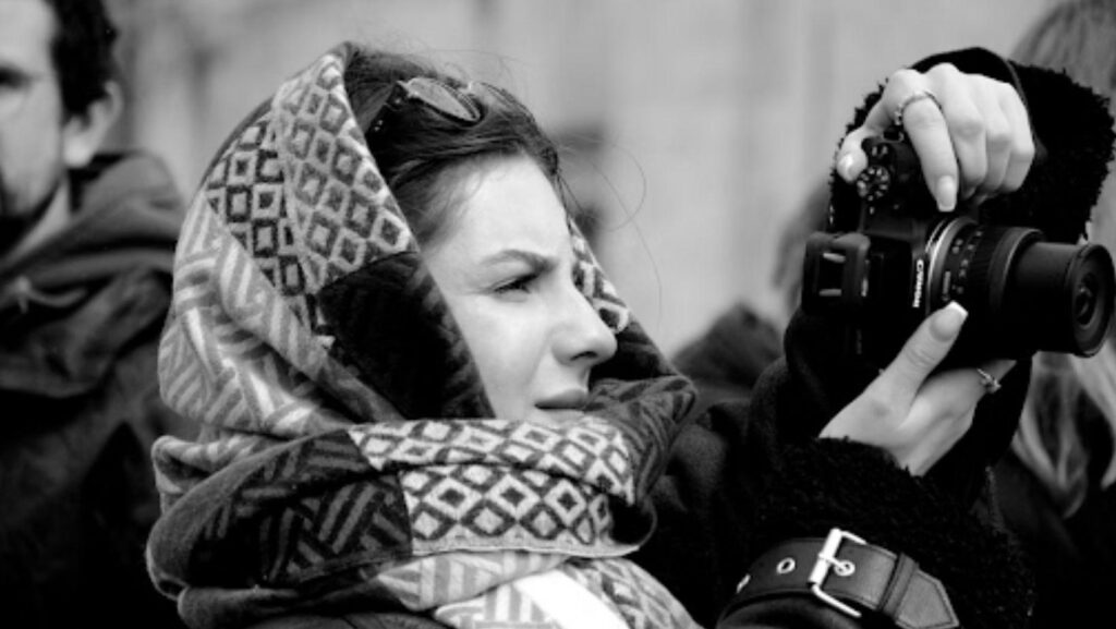 Portrait of a woman photographer taking photos outdoors. Black and white photo